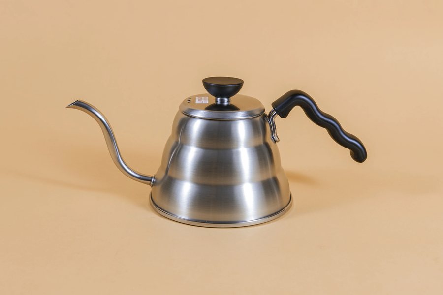 Hario V60 Buono stainless gooseneck kettle on a tan backdrop